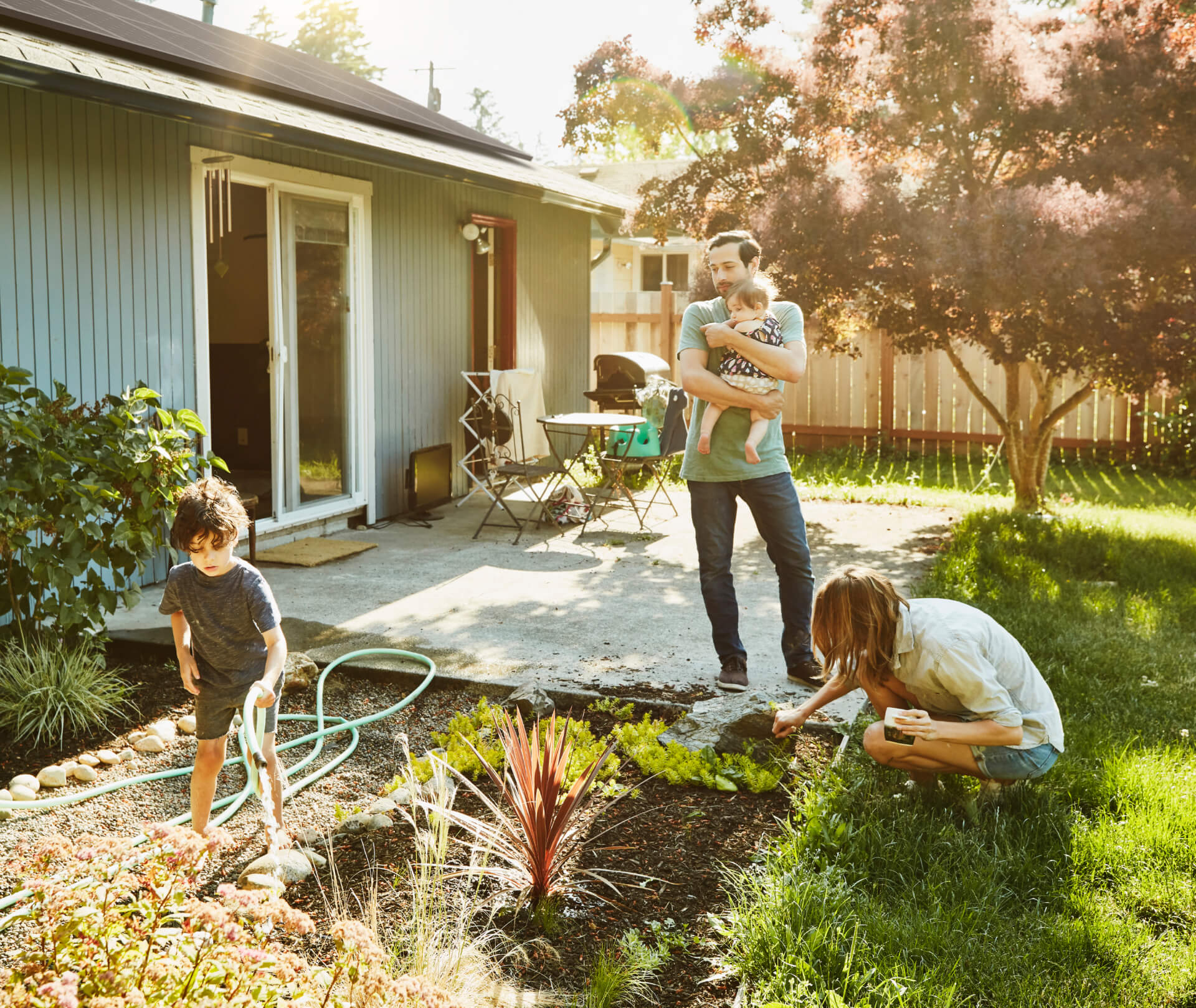 Family gardening in yard of home with solar panels